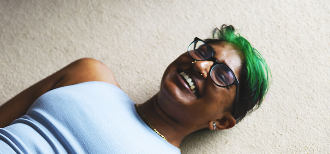 Zeenat laying on the floor inside her living room, smiling.