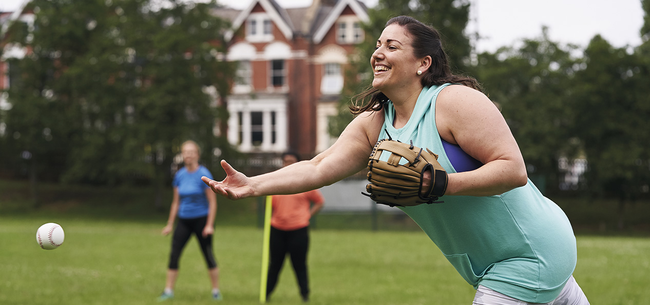 A woman pitches a softball during a game in a park