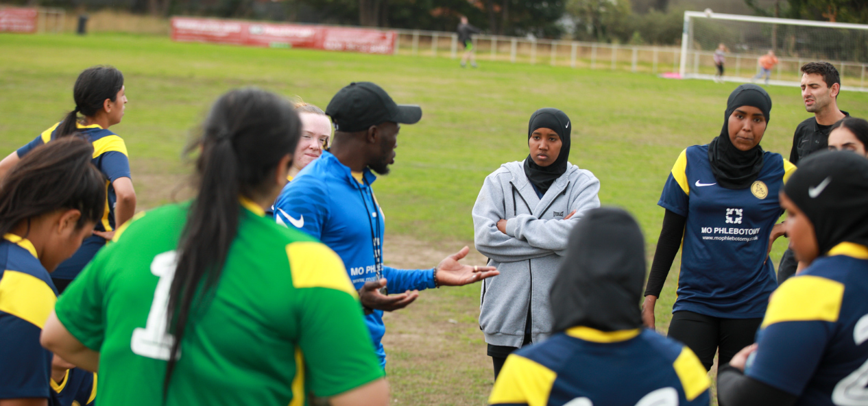 Girls football team in a huddle with coach