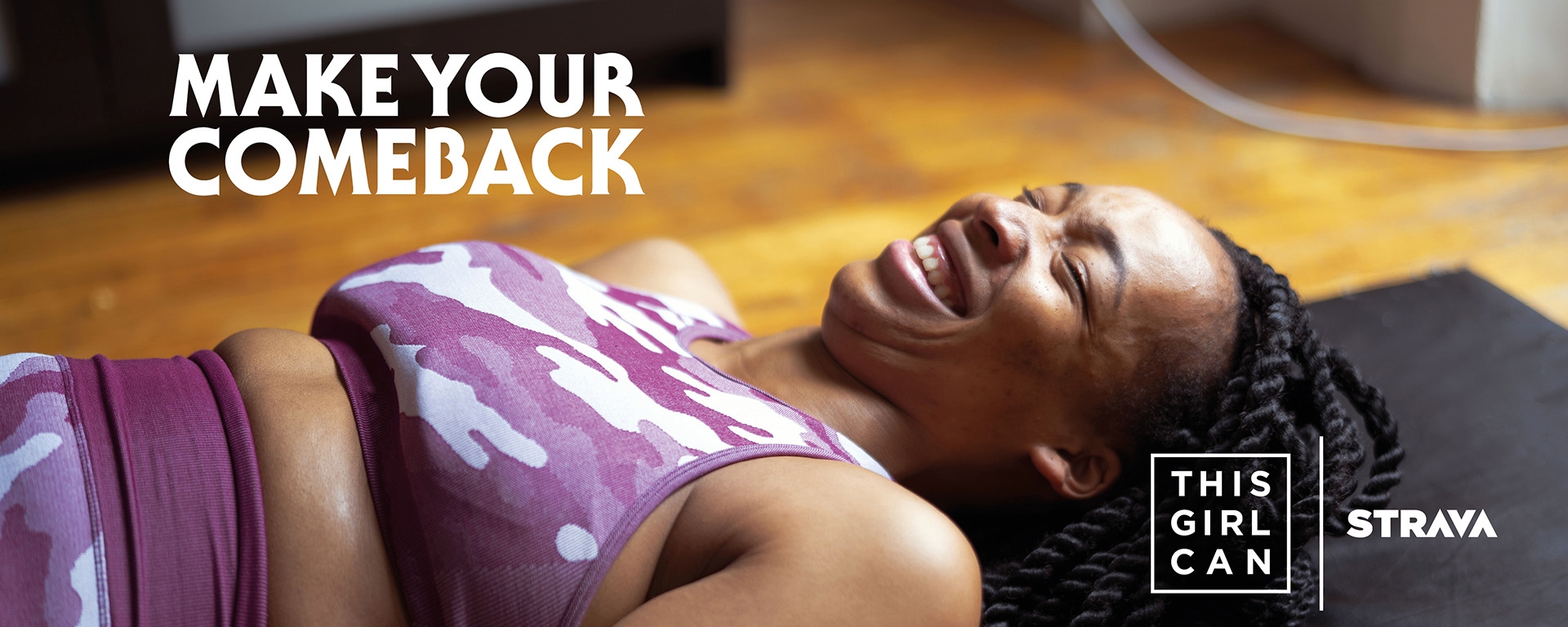 A woman smiles while lying on an exercise mat at home