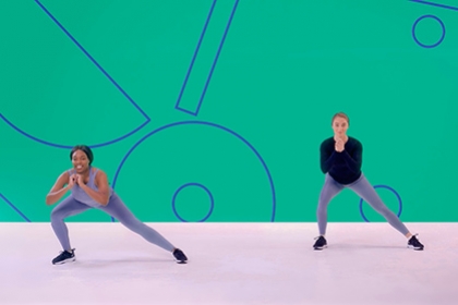 Two girls perform side lunges in an exercise class as part of a Studio You video