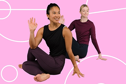 Two Studio You instructors stretch in front of a pink backdrop