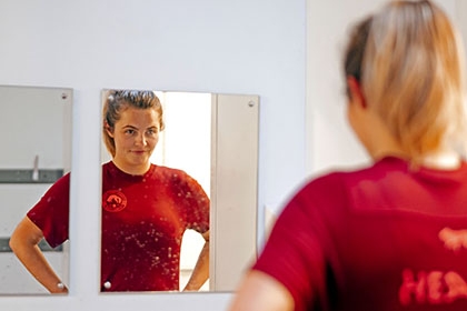 A woman wearing sports kit looks into a mirror in a changing room