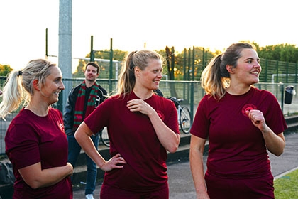 A group of women wait at the side of a football pitch to come on