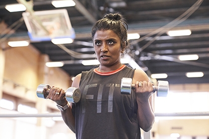 A woman does bicep curls with dumbbells in a gym