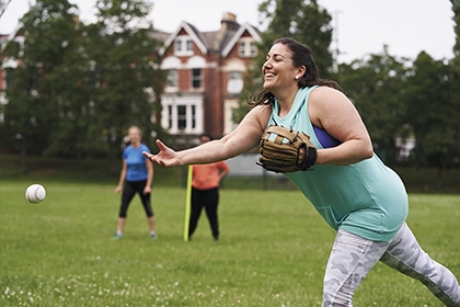 A woman pitches a softball during a game in a park