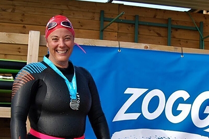 Alison smiles while wearing her swimming kit on an outdoors pool.