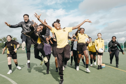Group of girls jumping on football pitch