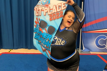 Tiffany holding a cheer banner in her cheerleader outfit.