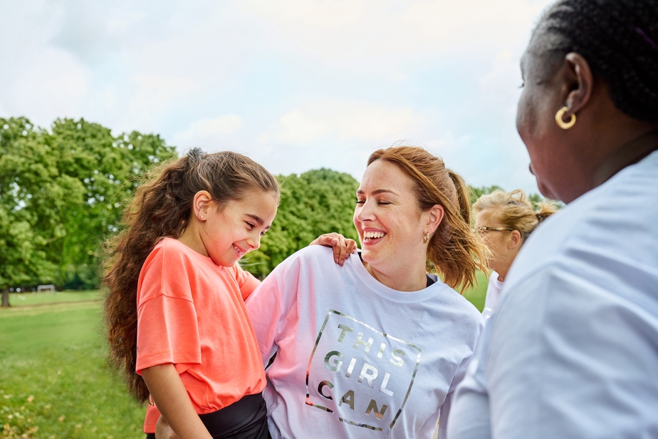 A mother holds her daughter, wearing This Girl Can activewear