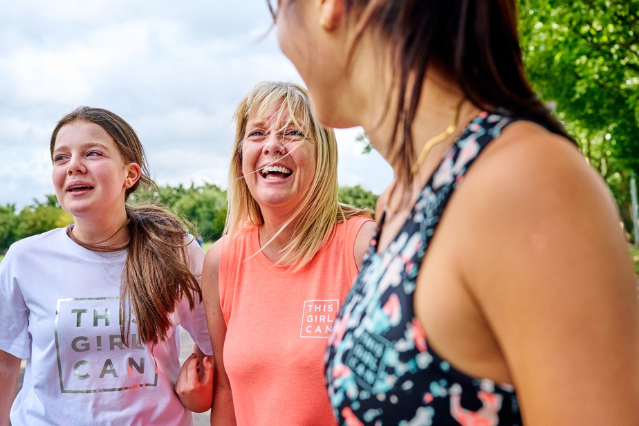 Two women and a teenage girl laugh and smile while wearing This Girl Can activewear
