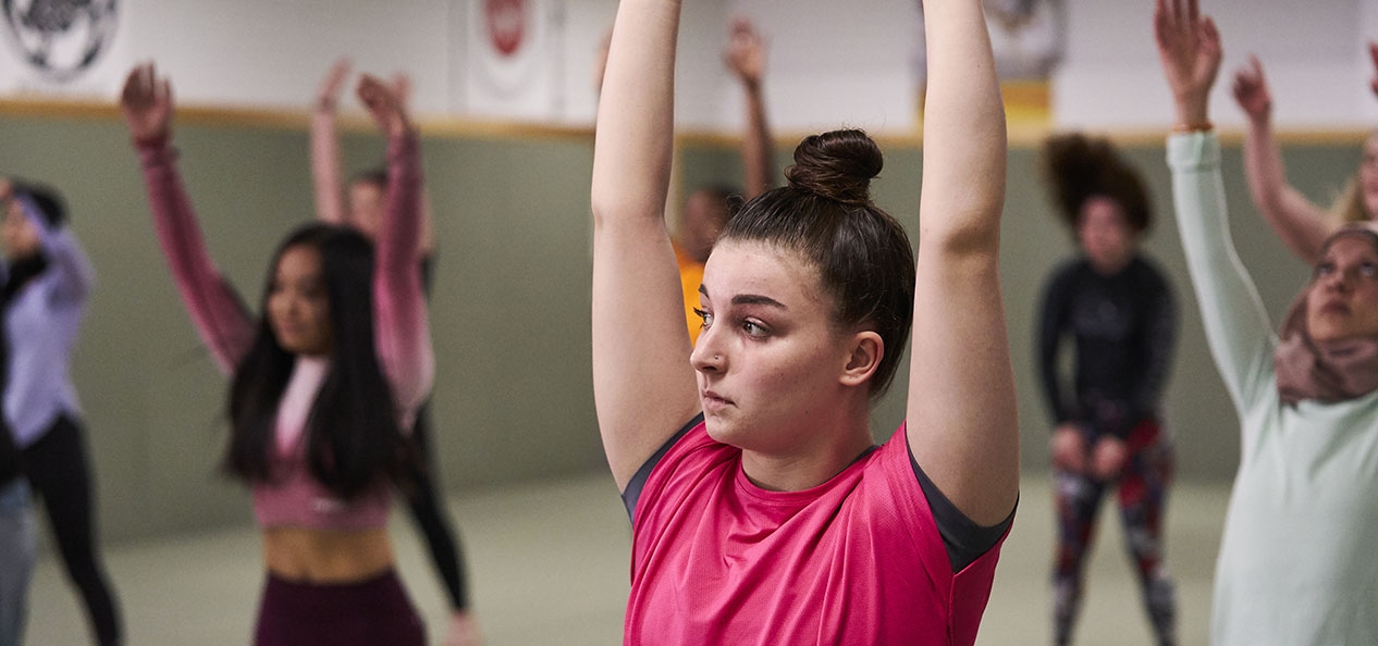A nervous-looking woman stretches in an exercise class