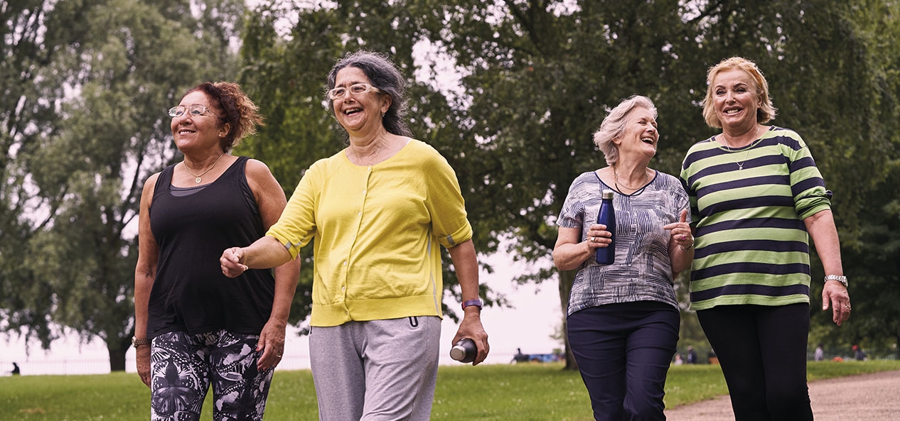 A group of women laughing and walking in a park