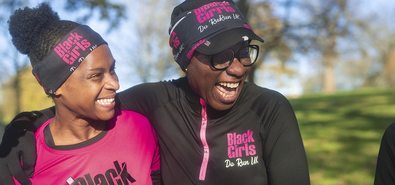 Two women from Black Girls Can Run, laugh while preparing to run