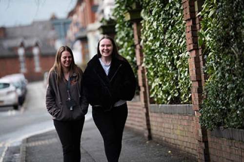 Two young women laugh as they walk down a street