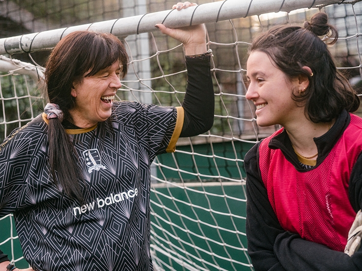 Two women chat while taking a break from playing football