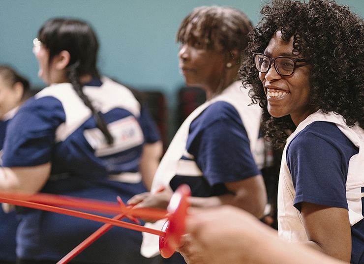A group of women try a fencing lesson using plastic swords