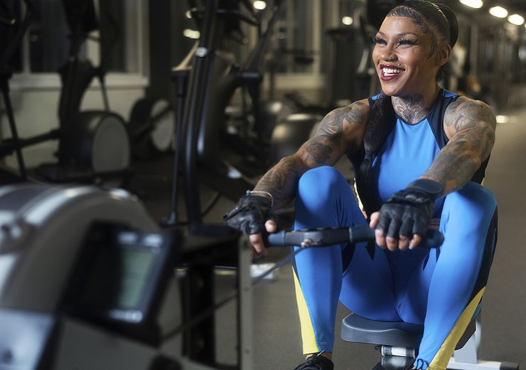 A smiling woman uses a rowing machine in a gym