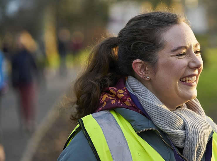 A woman in a high vis vest volunteers at a parkrun