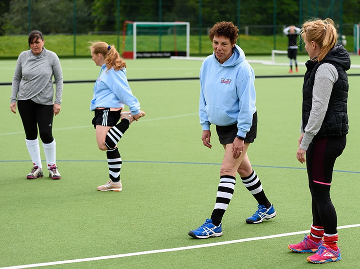 A woman coaches a women's hockey warm up