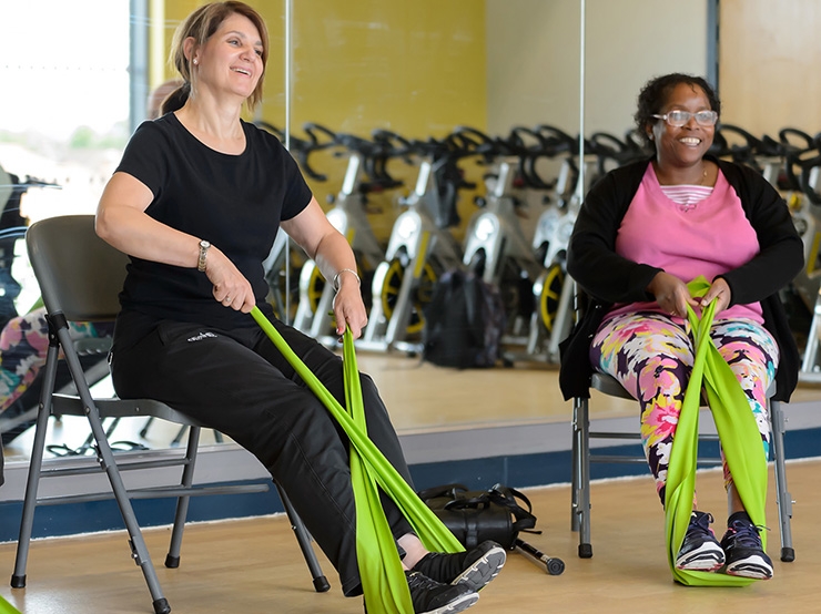 Two women use exercise bands to stretch