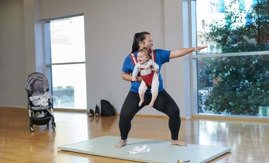 A mum exercises with her baby strapped to her front