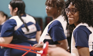 A group of women try a fencing lesson using plastic swords
