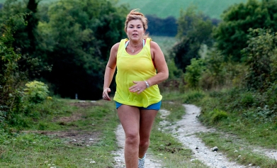 A woman runs up a hill in the countryside